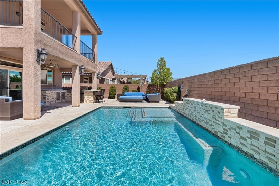 Wide pool view with the home's two stories and covered patio in the background, ready for entertaining.
