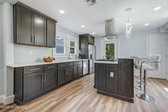 a kitchen with stainless steel appliances granite countertop wooden floors wooden cabinets and sink
