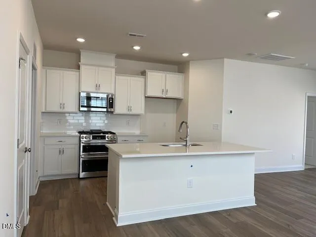 a kitchen with white cabinets and sink