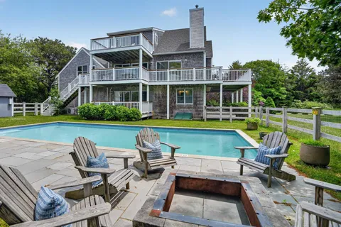 a view of a swimming pool with lawn chairs and a yard