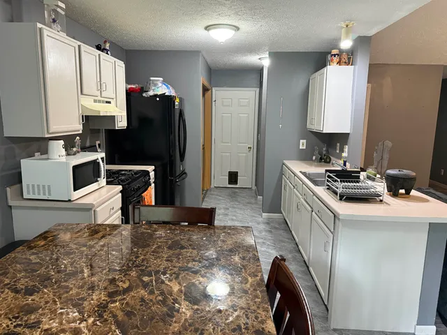 a kitchen with stainless steel appliances granite countertop a sink a stove and a refrigerator