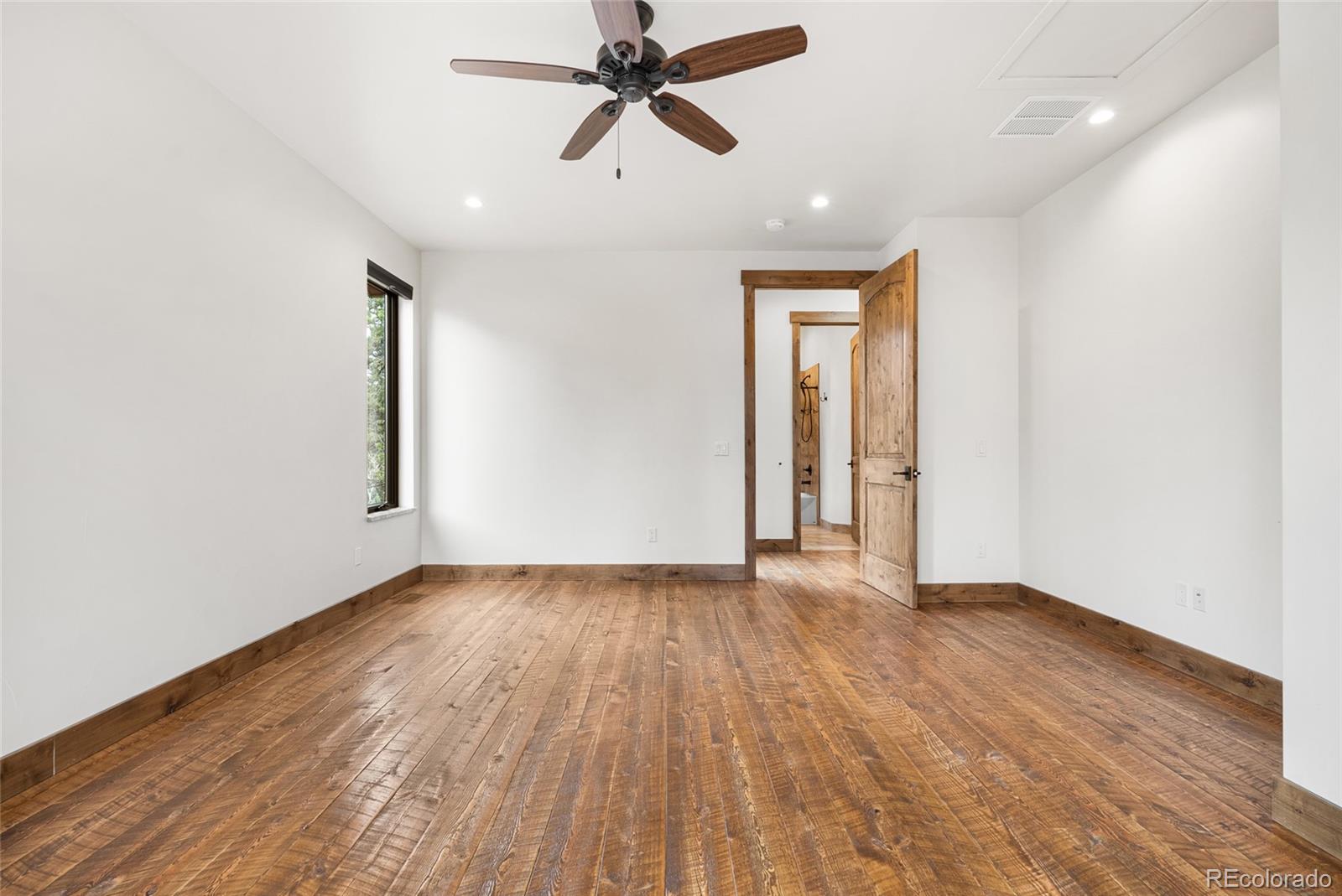 280 Double Tree Road Bailey, CO 80421 - Photo 24 of 43 an empty room with wooden floor ceiling fan and windows
