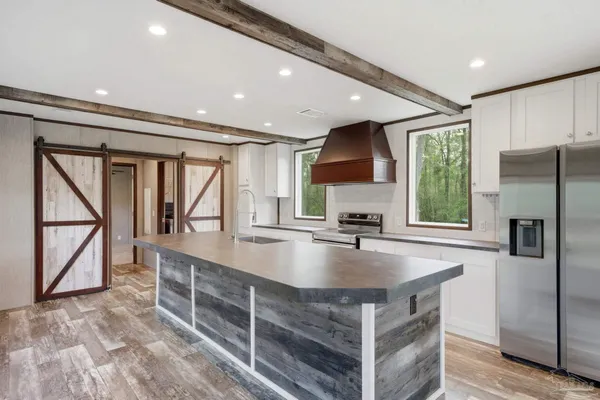 a kitchen with kitchen island a counter top space a sink stainless steel appliances and cabinets