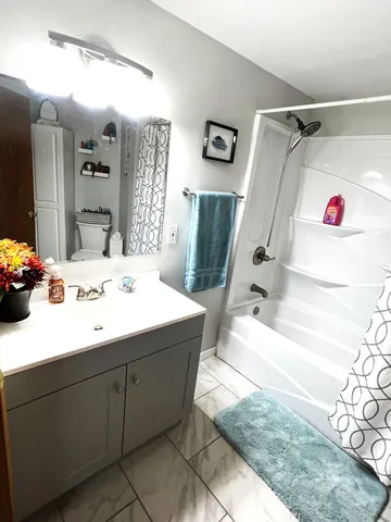 a bathroom with a sink vanity granite tub shower and a mirror