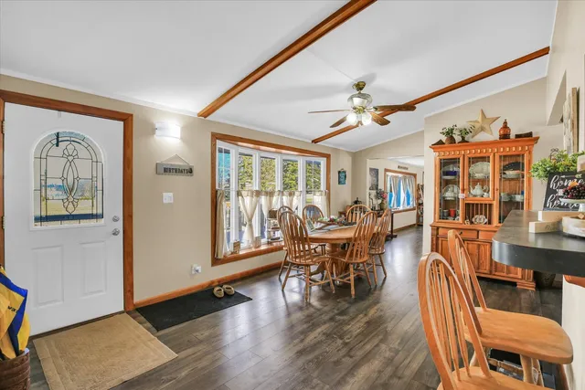 a dining room with wooden floor a chandelier a glass table and chairs
