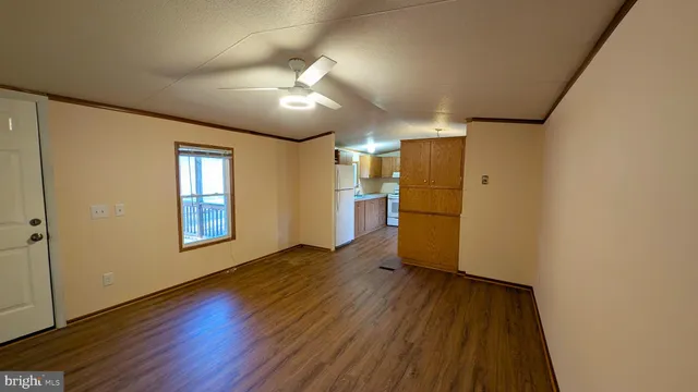 a view of empty room with wooden floor and fan
