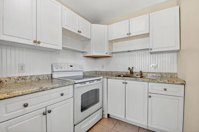 a kitchen with granite countertop white cabinets and white appliances