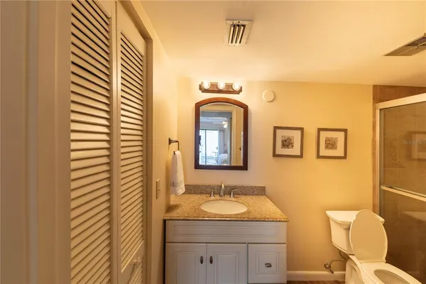 a bathroom with a granite countertop toilet sink and mirror