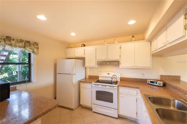 a kitchen with a refrigerator a stove a sink dishwasher and white cabinets with wooden floor