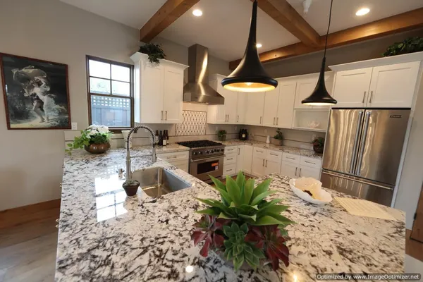 a kitchen with stainless steel appliances kitchen island granite countertop a sink a stove and a refrigerator