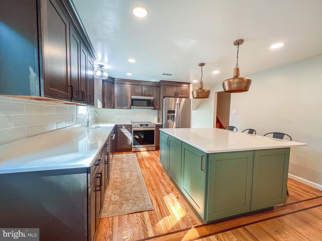 4643 Lerch Road Bensalem, PA 19020 - Photo 11 of 69 a kitchen with stainless steel appliances granite countertop a sink a stove and a wooden floors