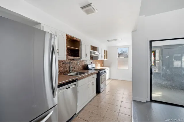 a large kitchen with a stove a sink dishwasher a refrigerator and a oven with wooden floor