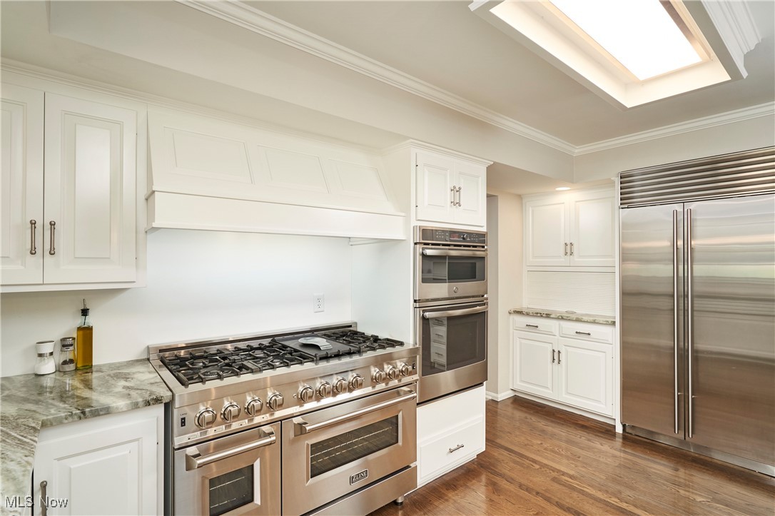 2285 Lancaster Road Akron, OH 44313 - Photo 13 of 48 Kitchen with high quality appliances, ornamental molding, white cabinetry, dark wood finished floors, and custom range hood