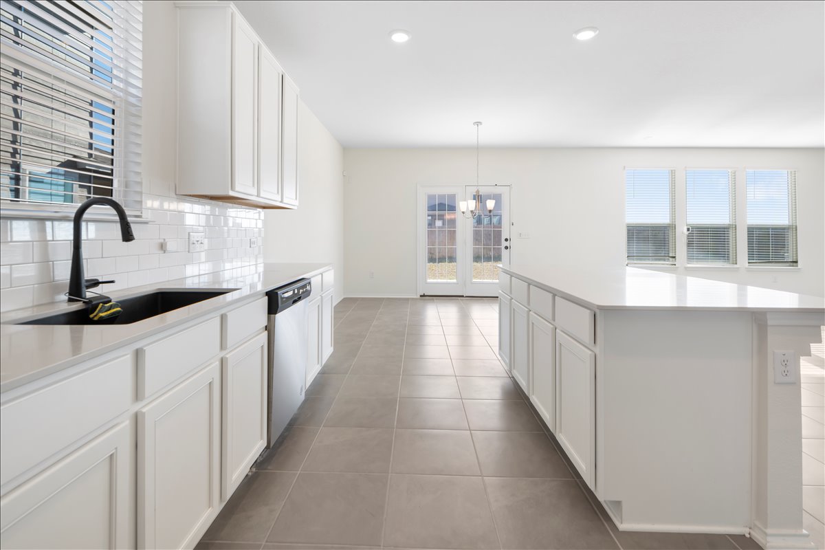 18501 Spotted Eagle Lane Elgin, TX 78621 - Photo 5 of 40 A well-appointed kitchen features pristine white cabinetry, ample counter space, and durable tiled flooring.