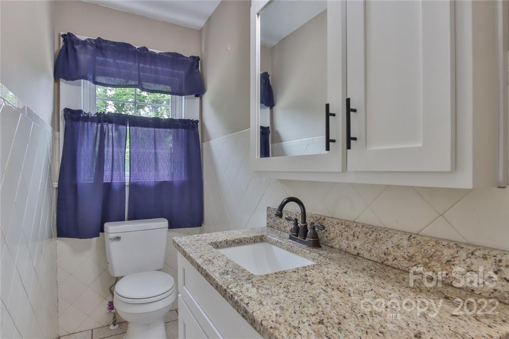 263 McCrary Place Lenoir, NC 28645 - Photo 19 of 40 a bathroom with a granite countertop toilet sink and mirror