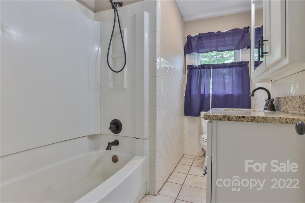 263 McCrary Place Lenoir, NC 28645 - Photo 20 of 40 a bathroom with a granite countertop sink a mirror and a bathtub