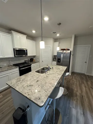 a kitchen with kitchen island a wooden floor and black appliances