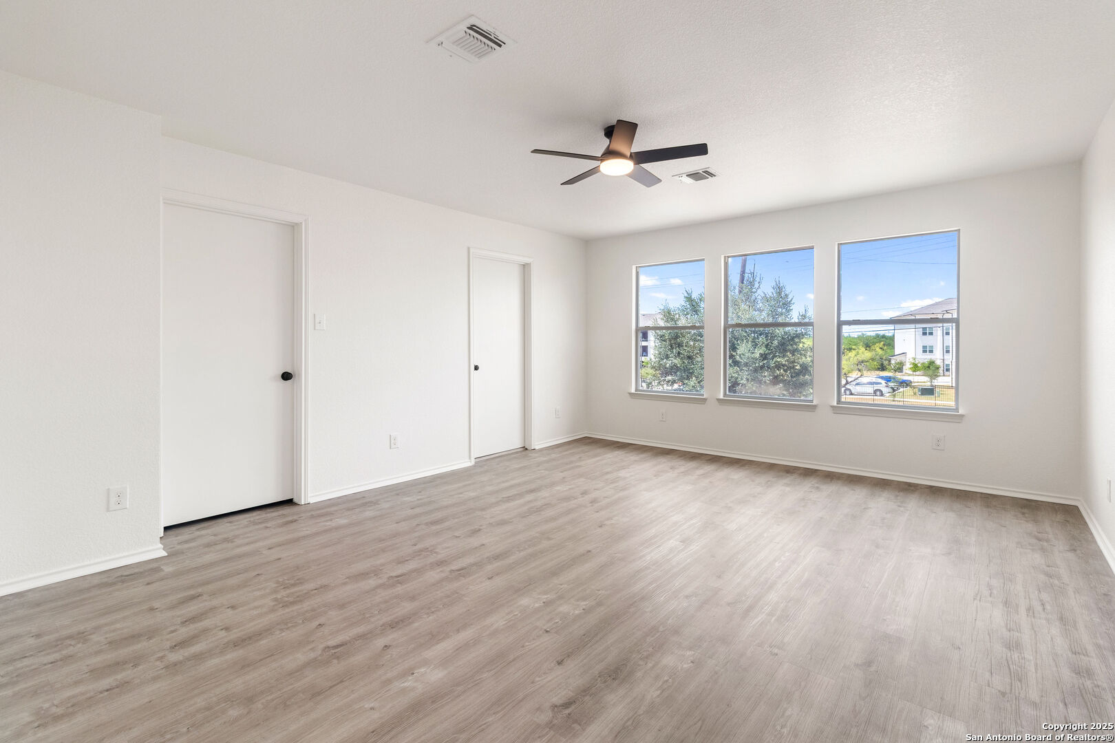 5015 Badland Beacon Converse, TX 78109 - Photo 13 of 23 an empty room with wooden floor chandelier fan and windows