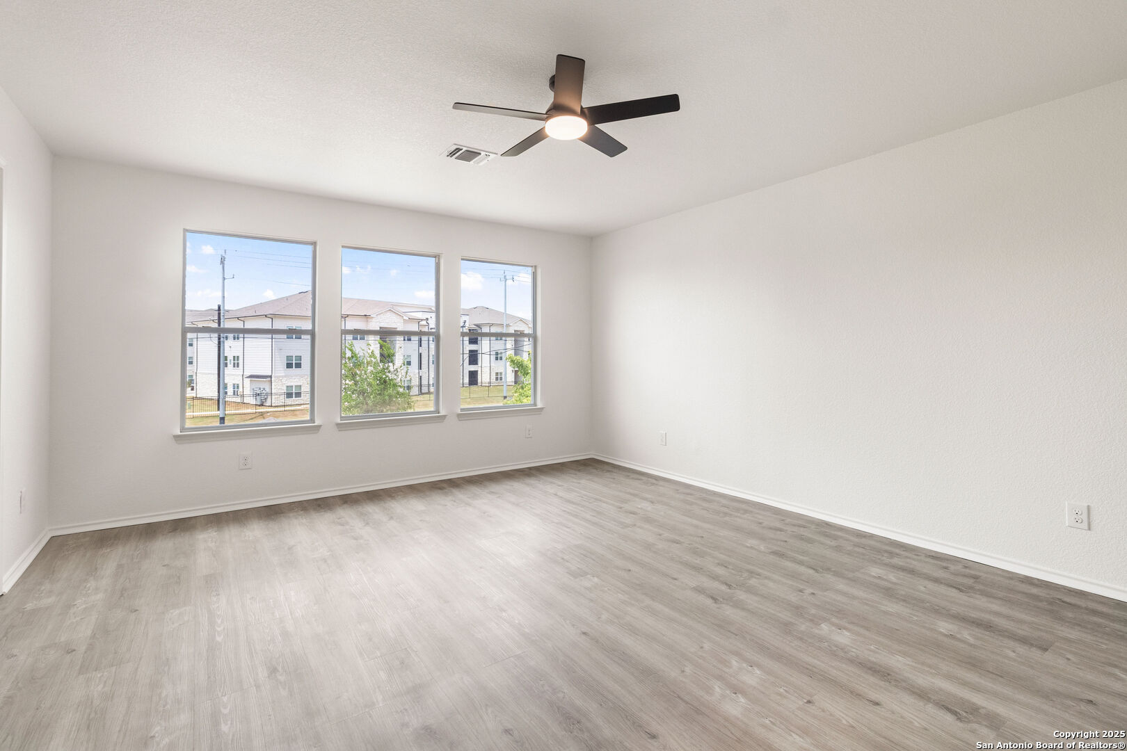 5015 Badland Beacon Converse, TX 78109 - Photo 14 of 23 an empty room with wooden floor chandelier fan and windows