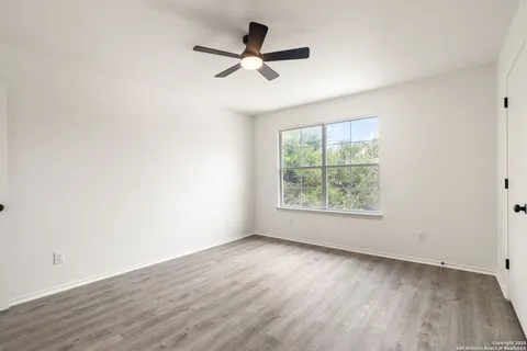 an empty room with wooden floor fan and windows
