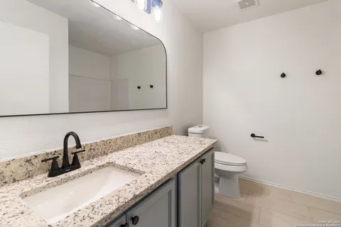 a bathroom with a granite countertop sink and a toilet