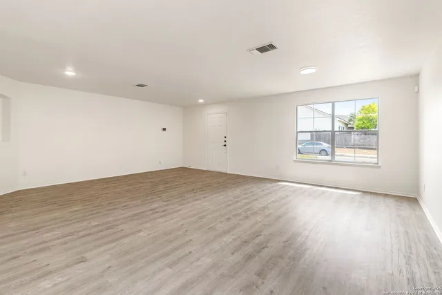 an empty room with wooden floor and windows