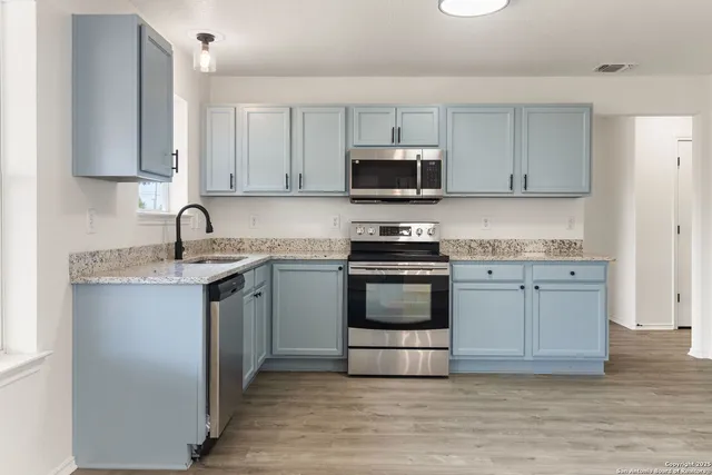 a kitchen with granite countertop a sink stainless steel appliances and white cabinets