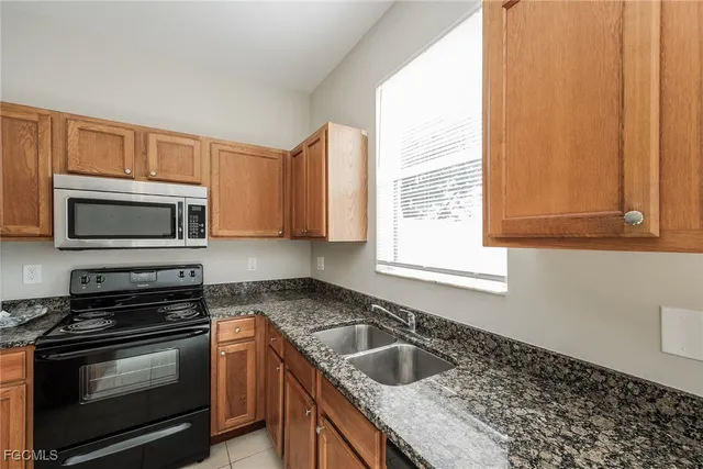a kitchen with granite countertop a sink stove and microwave
