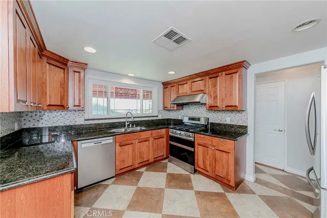 a kitchen with stainless steel appliances granite countertop a stove sink and cabinets