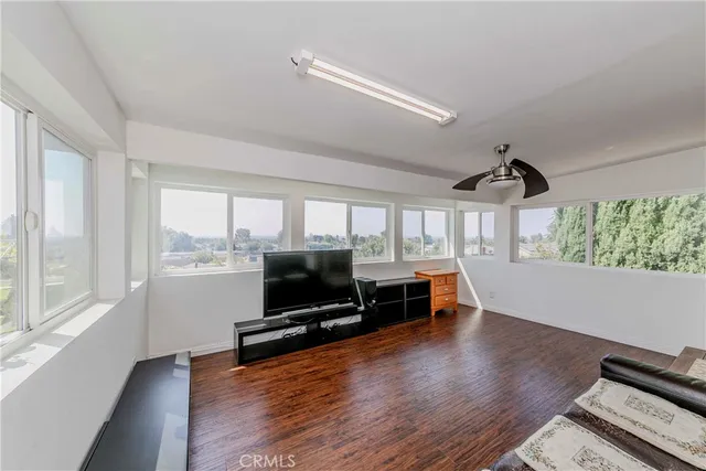 a living room with furniture a flat screen tv and floor to ceiling window
