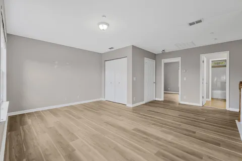 a view of an empty room with wooden floor and closet