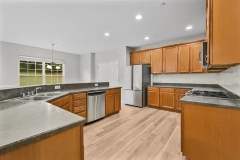 a kitchen with stainless steel appliances granite countertop a stove a sink dishwasher and a microwave oven with wooden floor