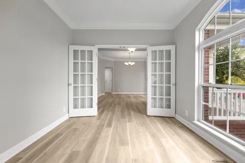 a view of an empty room with wooden floor and a window