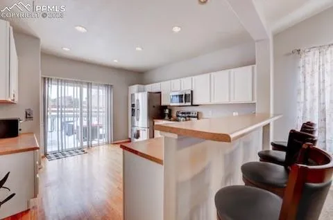 a kitchen with stainless steel appliances granite countertop a refrigerator a sink dishwasher a stove and white countertops with wooden floor