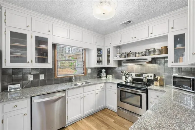 a kitchen with cabinets stainless steel appliances a sink and a window