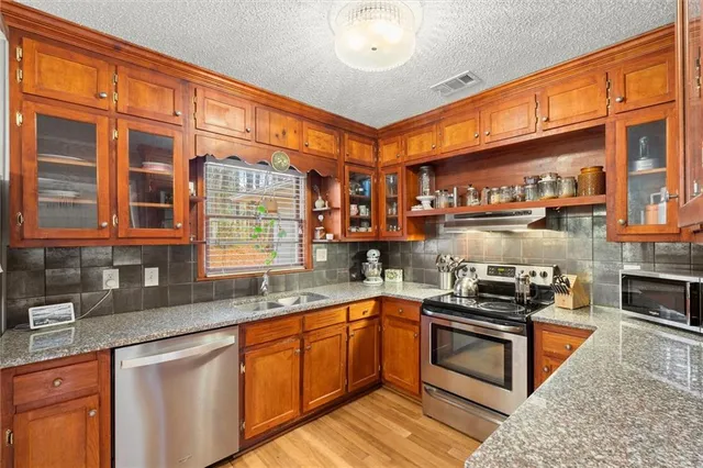 a kitchen with stainless steel appliances granite countertop a sink stove and cabinets