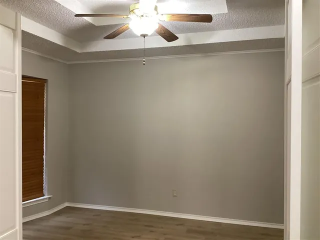 an empty room with wooden floor and fan