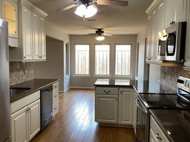 a kitchen that has a sink stainless steel appliances and window