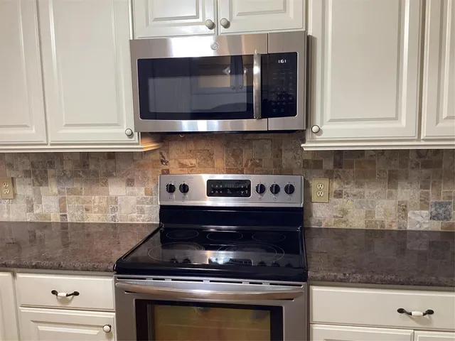 a kitchen with stainless steel appliances granite countertop white cabinets and stove