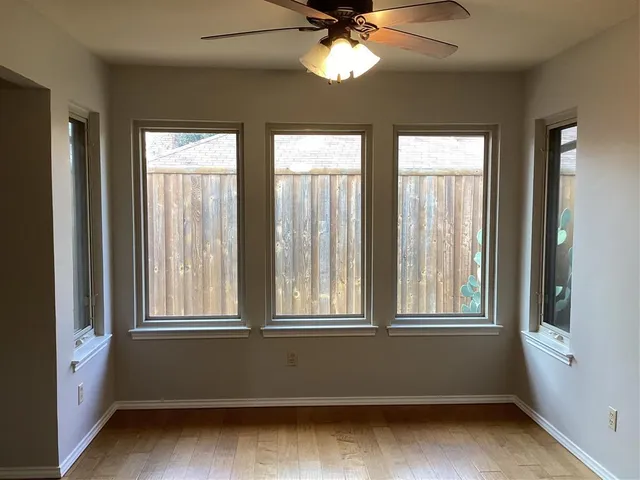 a view of an empty room with a window and wooden floor