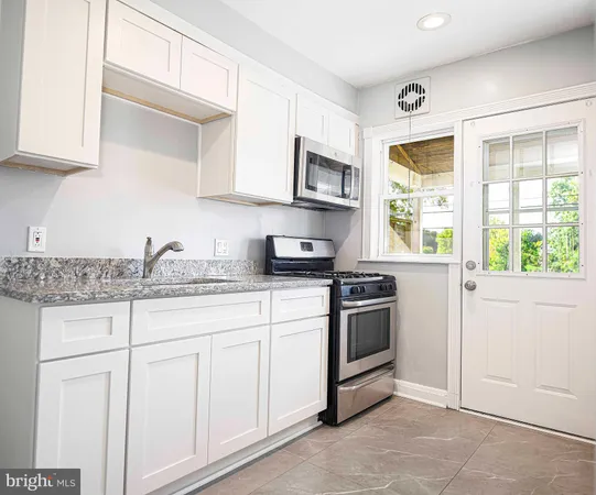 a kitchen with granite countertop white cabinets and appliances