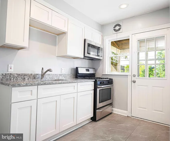 a kitchen with granite countertop white cabinets and appliances