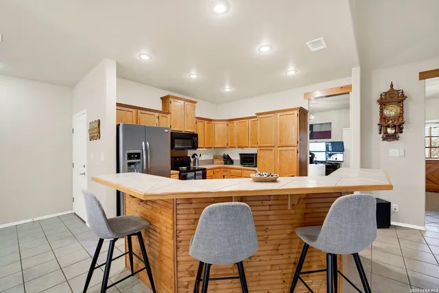 a kitchen with stainless steel appliances granite countertop a dining table chairs refrigerator and sink