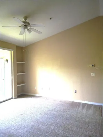 an empty room with a ceiling fan and carpet