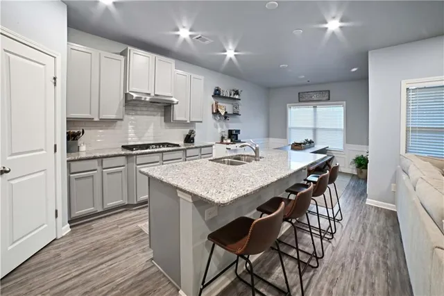 a kitchen with stainless steel appliances kitchen island granite countertop a table chairs sink and cabinets