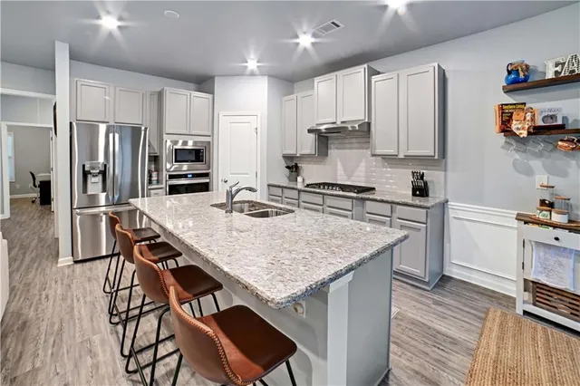 a kitchen with stainless steel appliances granite countertop a kitchen island a stove a table and chairs in it