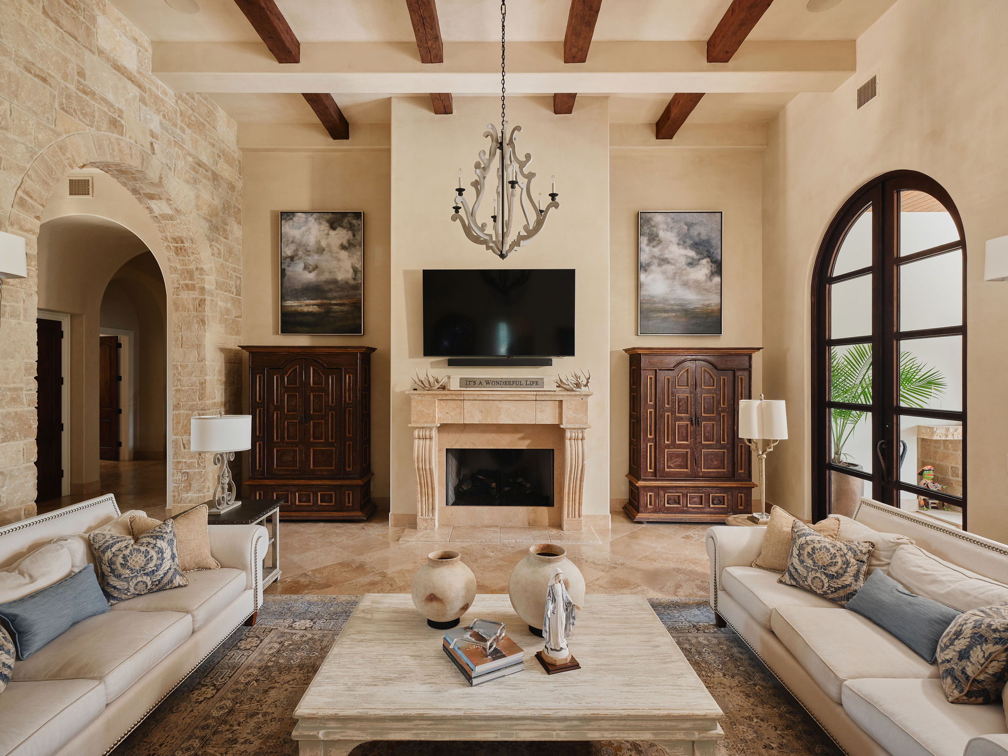433 Brandon Way Austin, TX 78733 - Photo 7 of 40 Elegant living area features exposed ceiling beams, an inviting fireplace, and arched doorways.