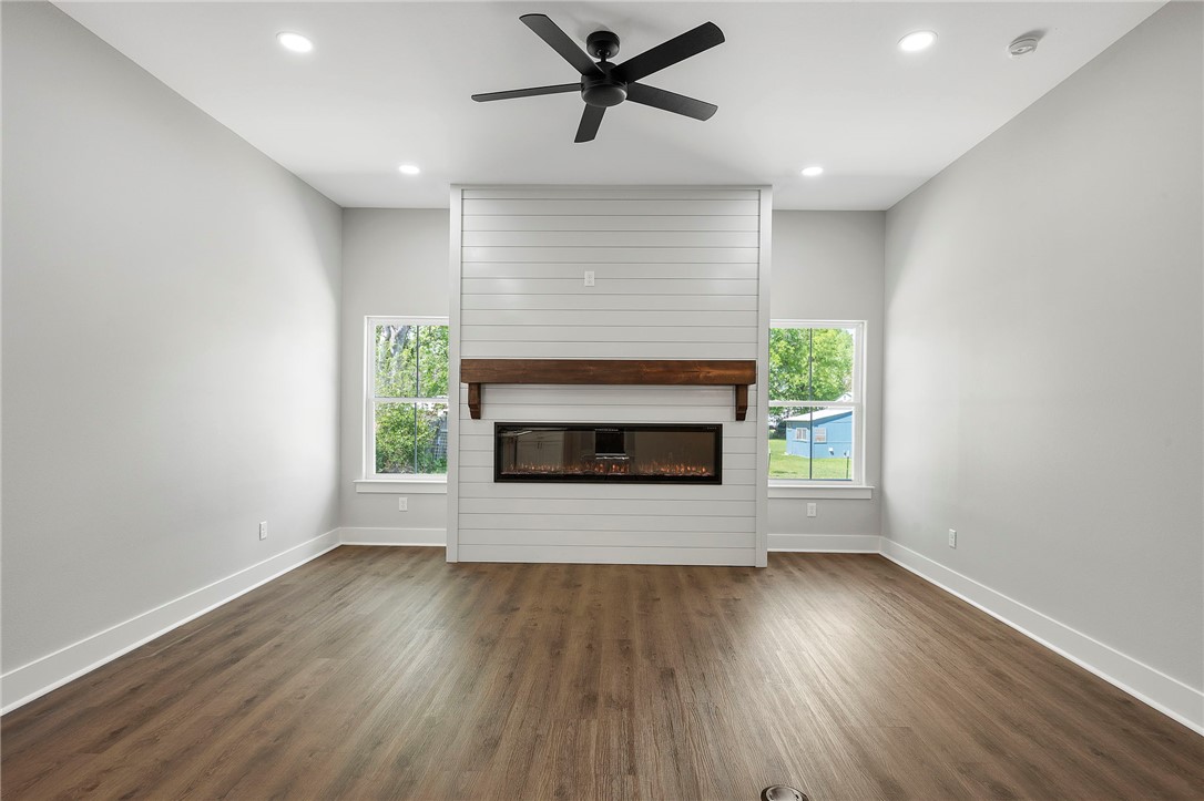 312 Morehead Street Franklin, TX 77856 - Photo 2 of 26 an empty room with wooden floor a fireplace and windows