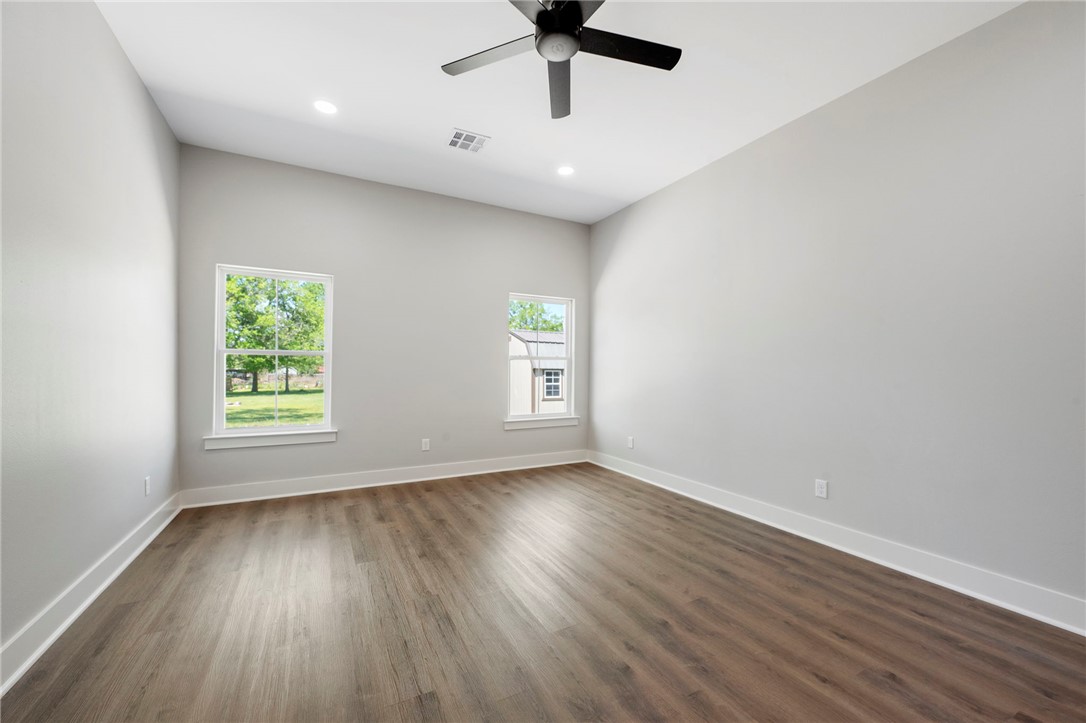 312 Morehead Street Franklin, TX 77856 - Photo 23 of 26 an empty room with wooden floor chandelier fan and windows