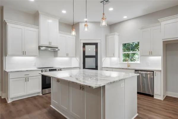 a kitchen with kitchen island granite countertop a sink stove and refrigerator